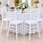 White Chiavari banquet chairs arranged around a table at an elegant wedding reception.